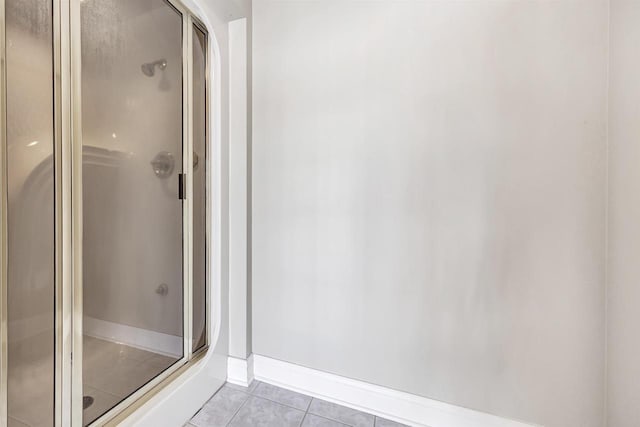 full bath with a shower stall, baseboards, and tile patterned floors