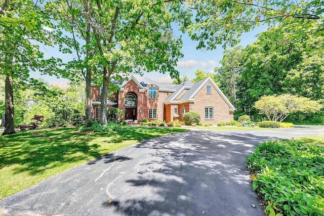 view of front of house featuring brick siding, aphalt driveway, and a front yard