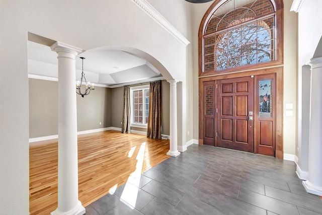 foyer entrance featuring decorative columns, baseboards, and wood finished floors