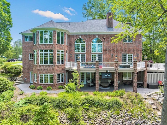 rear view of property with a patio, brick siding, and a chimney