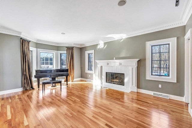 unfurnished living room featuring ornamental molding, a premium fireplace, light wood-type flooring, and visible vents