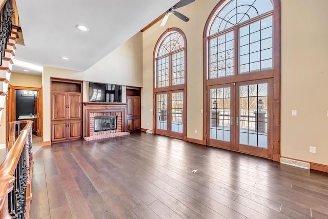 unfurnished living room featuring french doors, visible vents, dark wood-type flooring, a brick fireplace, and baseboards