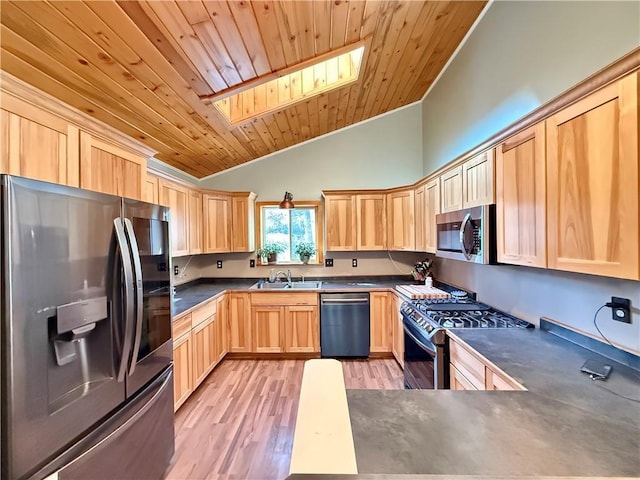 kitchen with dark countertops, lofted ceiling with skylight, stainless steel appliances, light brown cabinetry, and light wood-type flooring