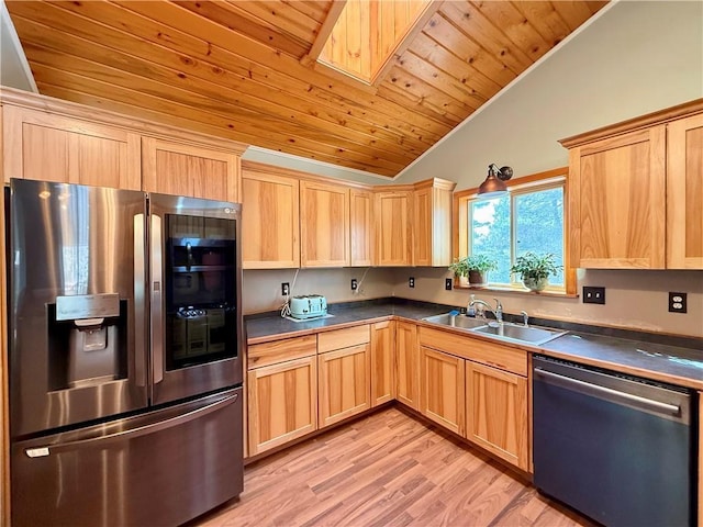 kitchen featuring stainless steel appliances, dark countertops, a sink, and light brown cabinetry