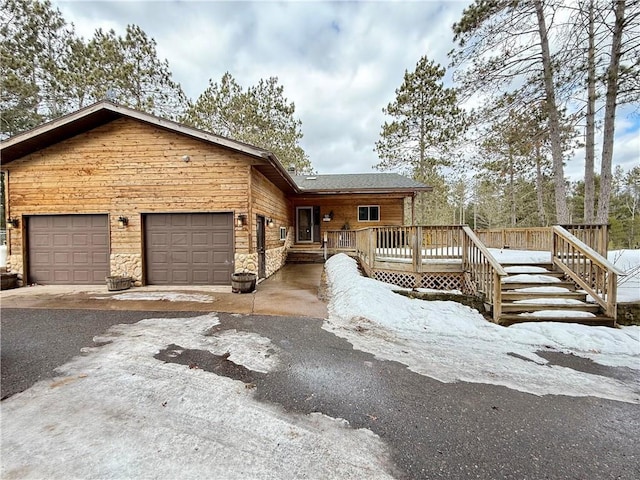 view of front of house featuring stone siding, an attached garage, and a wooden deck