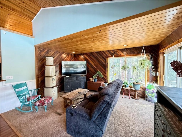 carpeted living area featuring lofted ceiling, wooden ceiling, wood walls, visible vents, and wainscoting