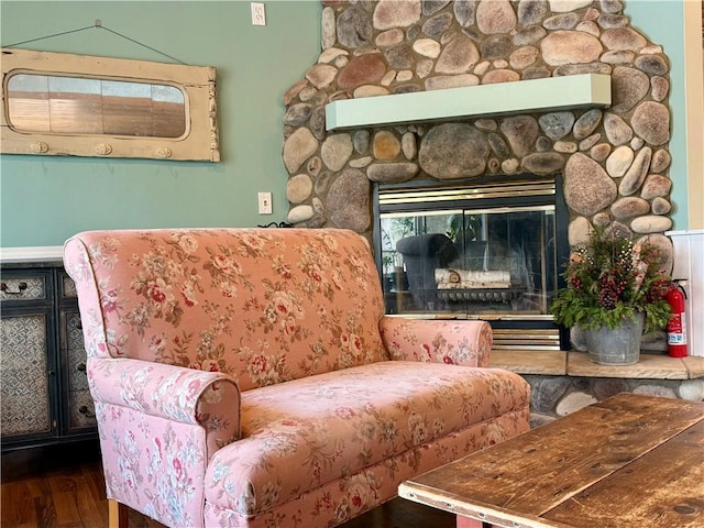 sitting room with a stone fireplace and wood finished floors