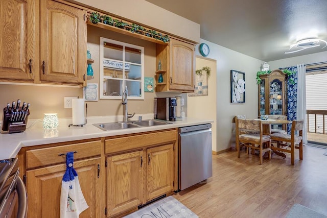 kitchen with range, light wood-style flooring, light countertops, stainless steel dishwasher, and a sink