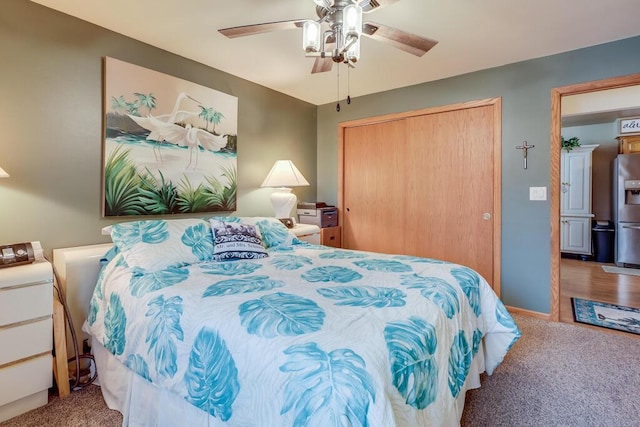 bedroom with ceiling fan, carpet floors, a closet, and stainless steel fridge with ice dispenser