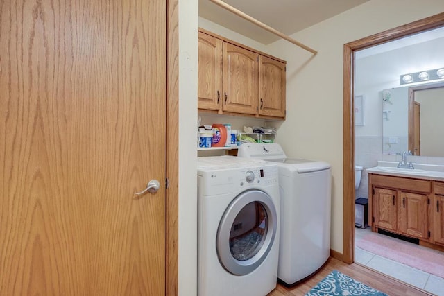 clothes washing area featuring cabinet space, tile walls, a sink, and independent washer and dryer