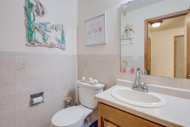 bathroom featuring toilet, tile walls, and vanity