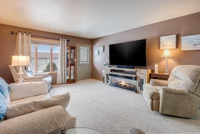 living area with carpet, a glass covered fireplace, and baseboards