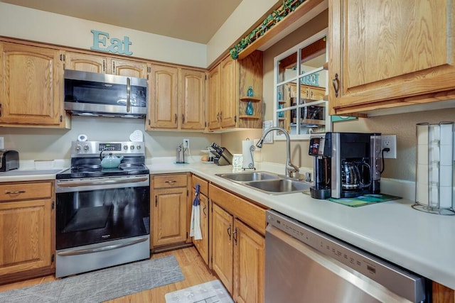 kitchen featuring light wood-type flooring, appliances with stainless steel finishes, light countertops, and a sink