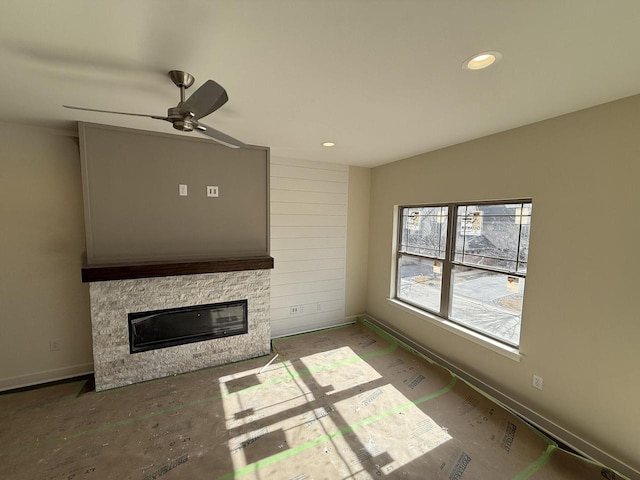 unfurnished living room featuring recessed lighting, ceiling fan, a stone fireplace, and baseboards