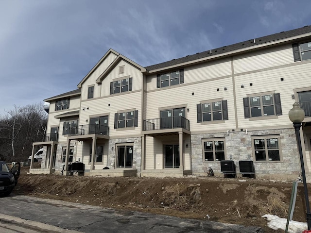 back of property with stone siding and central AC unit