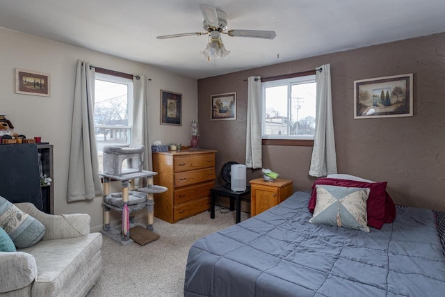 bedroom featuring a ceiling fan, light colored carpet, and a textured wall