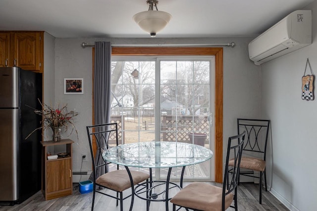 dining area with light wood-type flooring, a baseboard radiator, and a wall mounted air conditioner