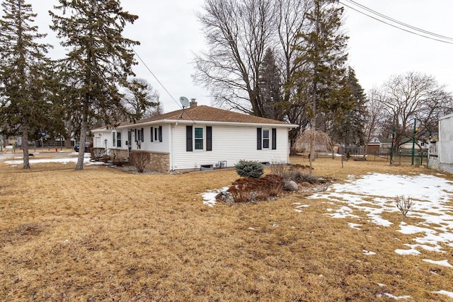 view of side of property featuring a yard, fence, and a chimney