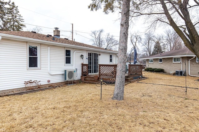 rear view of property with a yard, central AC unit, ac unit, and a chimney