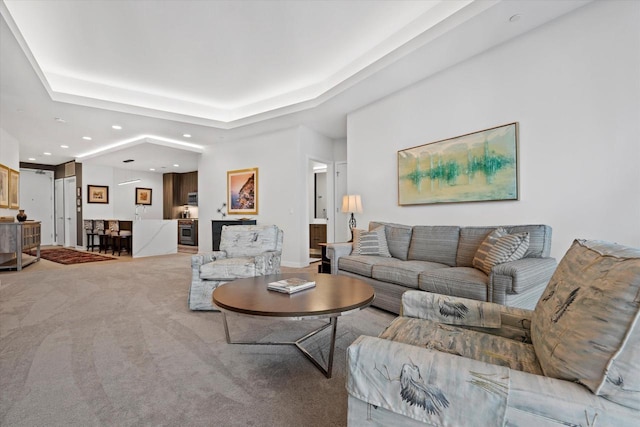 carpeted living area with a tray ceiling and recessed lighting