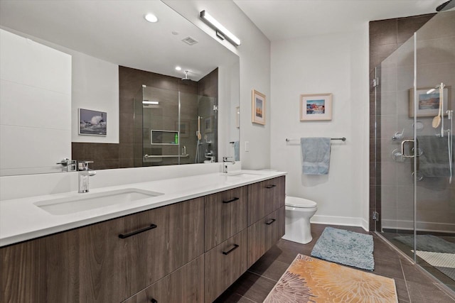 bathroom featuring double vanity, a sink, toilet, and a shower stall