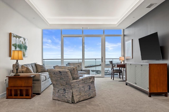 carpeted living area with expansive windows, visible vents, a raised ceiling, and a wealth of natural light