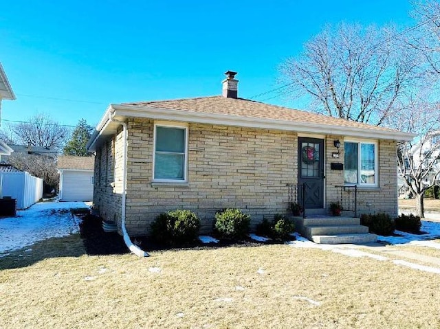 view of front facade featuring brick siding, a chimney, a front lawn, and fence