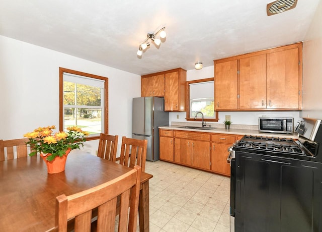 kitchen with black range with gas cooktop, a sink, visible vents, light countertops, and freestanding refrigerator