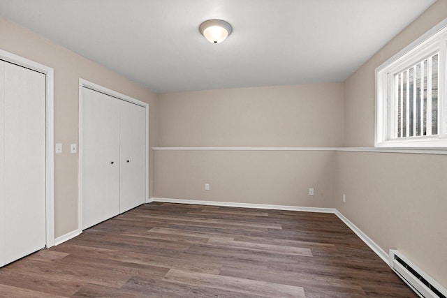 unfurnished bedroom featuring a baseboard radiator, baseboards, and wood finished floors