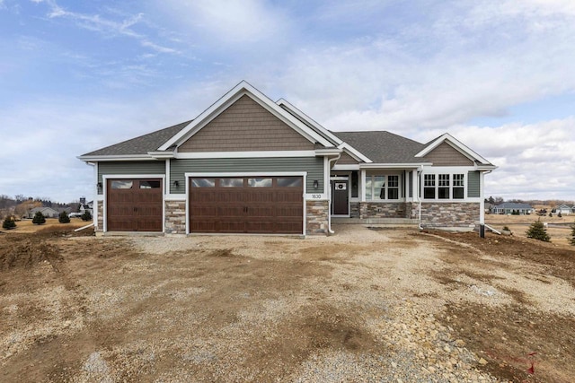 craftsman-style home featuring dirt driveway, stone siding, and an attached garage