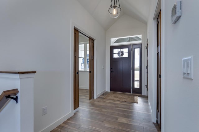 entrance foyer featuring plenty of natural light, baseboards, vaulted ceiling, and wood finished floors