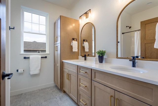 full bath with double vanity, baseboards, and a sink