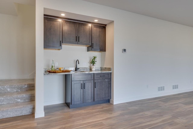 bar with baseboards, recessed lighting, a sink, and light wood-style floors