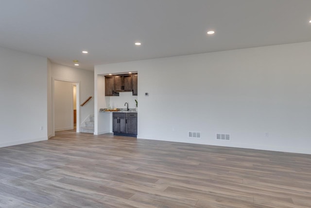 unfurnished living room featuring recessed lighting, visible vents, a sink, and stairway