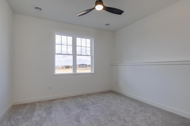 carpeted spare room with visible vents, baseboards, and a ceiling fan