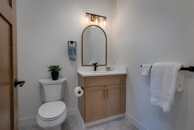 bathroom with toilet, vanity, and baseboards