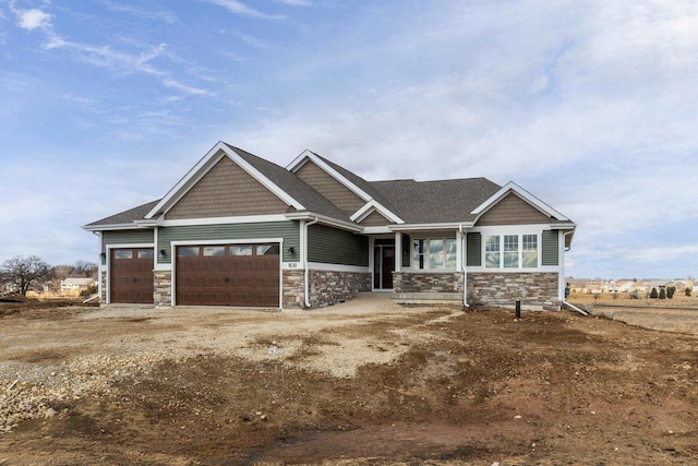 craftsman-style home with a garage, stone siding, and dirt driveway