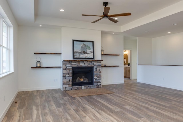 unfurnished living room featuring a tray ceiling, plenty of natural light, wood finished floors, and baseboards