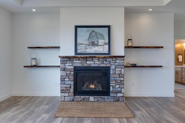 details with recessed lighting, baseboards, wood finished floors, and a stone fireplace