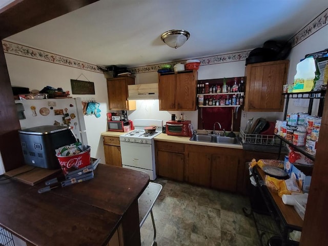 kitchen with brown cabinetry, white appliances, a sink, and under cabinet range hood