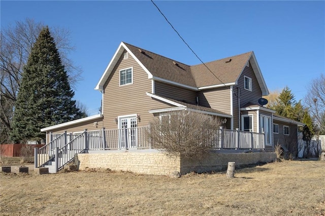 rear view of house featuring a deck and roof with shingles