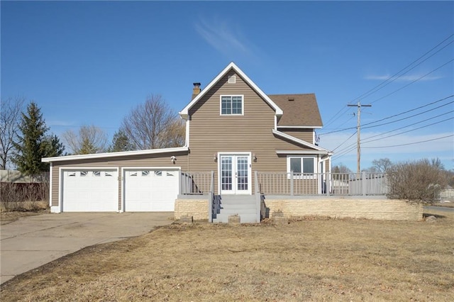 view of front of property with a garage, french doors, a chimney, and concrete driveway