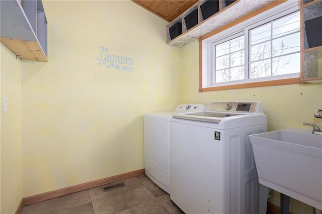 laundry room featuring light tile patterned floors, laundry area, a sink, baseboards, and independent washer and dryer