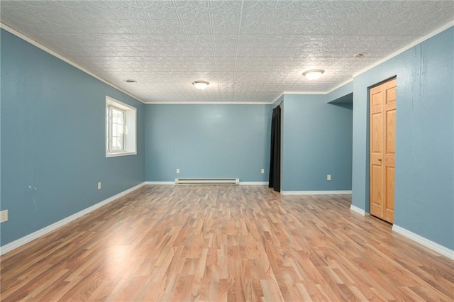 spare room featuring a baseboard heating unit, crown molding, baseboards, and wood finished floors