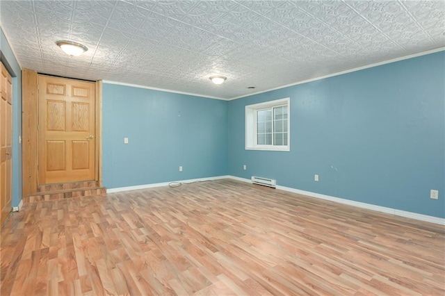 unfurnished room with baseboard heating, wood finished floors, and baseboards