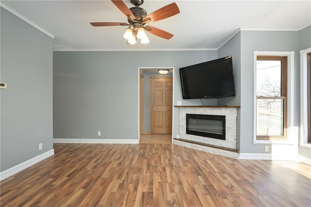 unfurnished living room with crown molding, a fireplace, wood finished floors, and baseboards