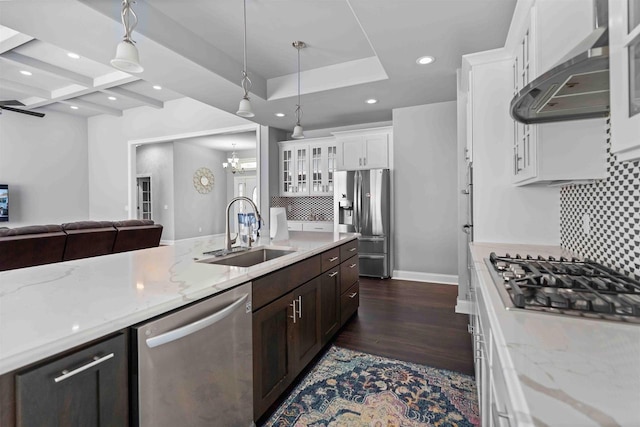 kitchen with a sink, tasteful backsplash, stainless steel appliances, wall chimney range hood, and glass insert cabinets