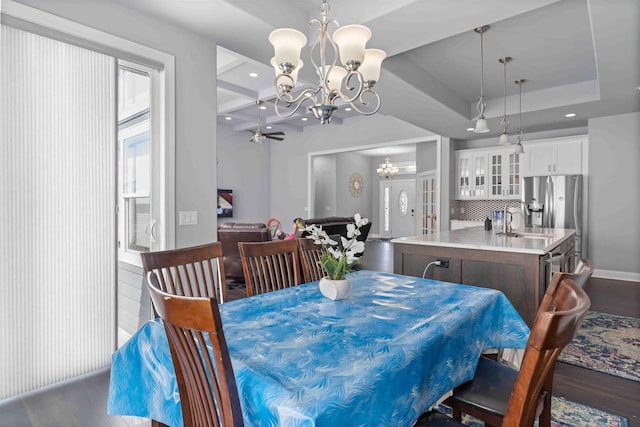 dining area featuring dark wood-type flooring, ceiling fan with notable chandelier, a tray ceiling, recessed lighting, and french doors