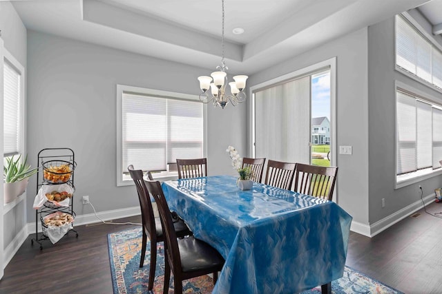 dining area with a healthy amount of sunlight, baseboards, a tray ceiling, and wood finished floors