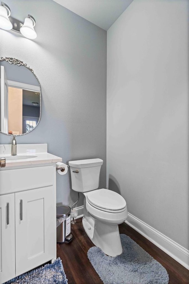 bathroom with baseboards, toilet, wood finished floors, and vanity